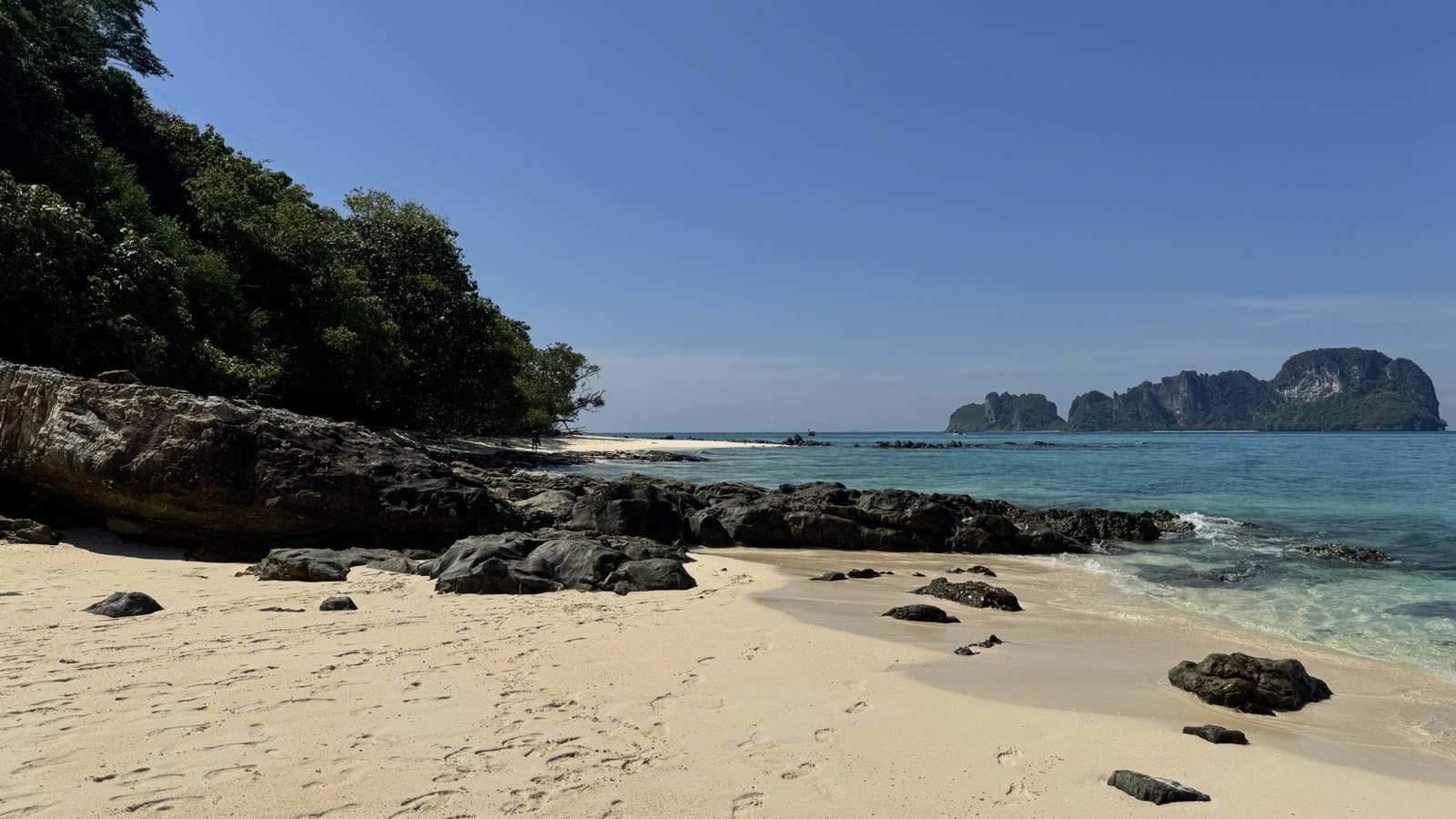 A quiet tropical beach with limestone headlands rising out of turquoise water