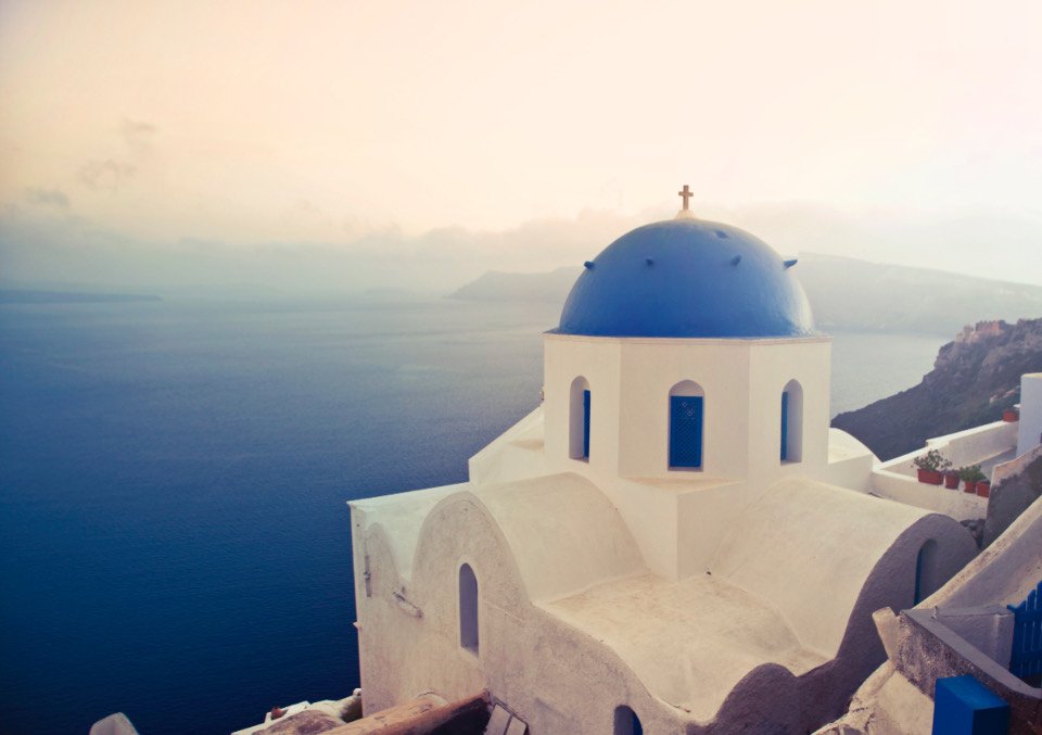 A blue-domed white church above the caldera on Santorini